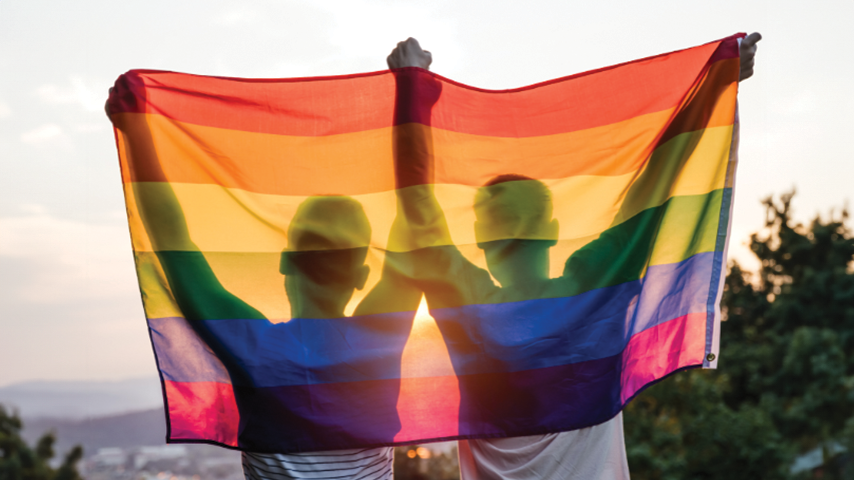 Two men holding up a rainbow flag